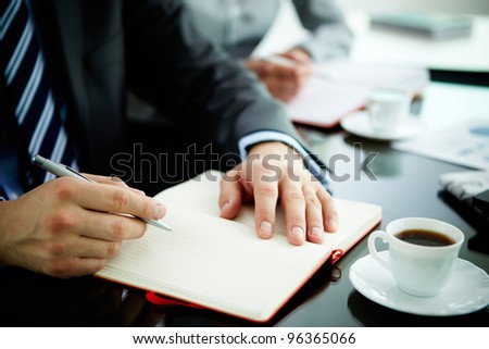 Image of male hand with pen over open notebook during planning work