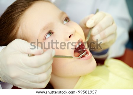 Patient with opened mouth being examined by a dentist