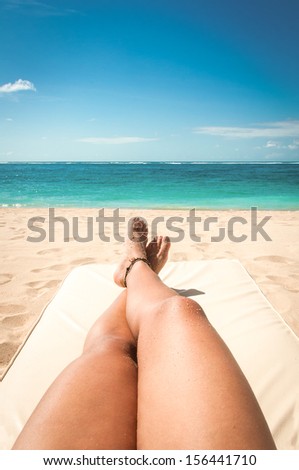 Young woman legs sunbathing on the beach