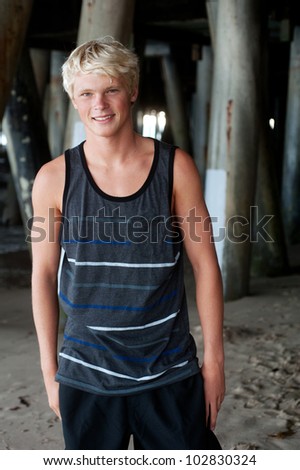 portrait of a teenage surfer boy at the beach under the pier