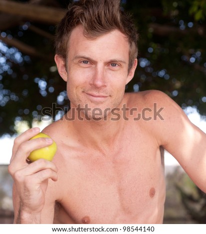 portrait of a young healthy man outside holding apple
