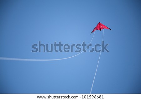 Red kite flies on sky, white string arch