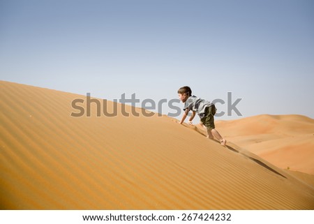 Young boy plays among sand dunes in desert