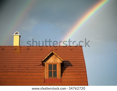 Rainy weather, clouds, rainbow, and a wet roof of a house.
