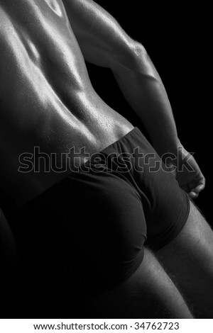 Low key picture of a sexy man\'s back and butt.