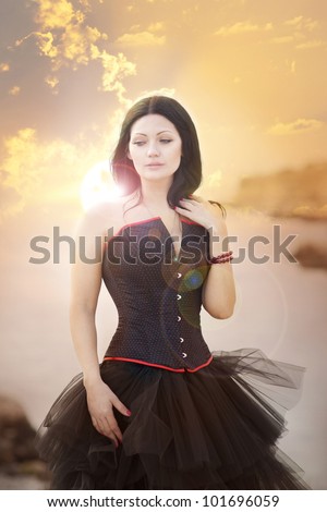 beautiful slim rich woman in luxurious dress on sunset beach. Fashion romantic stylish arabian young girl with long glossy healthy hair. Gothic bride Spring - summer