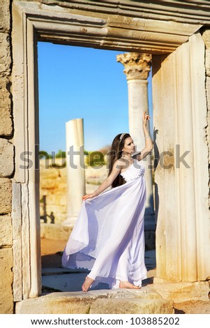 beautiful slim bride in luxury dress on sunset near ancient ruins in wedding day. young woman in Greek  goddess style with diamond tiara and jewelery. Fashion stylish romantic girl with glossy hair.