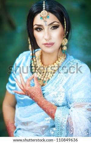 Beautiful young indian woman in traditional clothing with bridal makeup and jewelry. gorgeous brunette bride traditionally dressed Outdoors in India. Girl bollywood  dancer in Sari and henna on hands