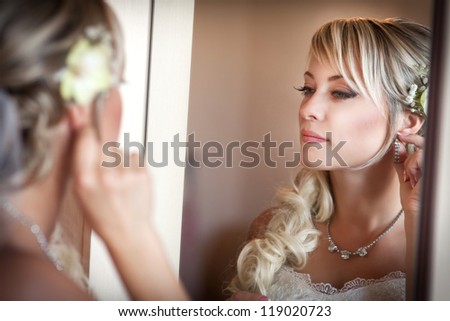 beautiful bride blond in white wedding dress with hairstyle and bright makeup. Happy sexy girl waiting for groom. Romantic lady in bridal dress and flowers in hair have final preparation for wedding