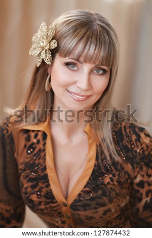 elegant happy middle aged woman with bright makeup and fashion hairstyle posing at home. Rich blond stylish businesswoman smiling. cheerful middle aged woman with golden flower  in Valentines day