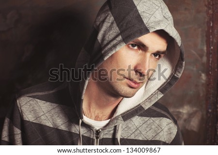 Handsome man portrait on graffiti grunge wall at street in casual sweater. Hip hop dancer angry guy in jacket. Hooligan male mob. Male Fashion. brutal sexy stylish guy model Rapper or rnd singer
