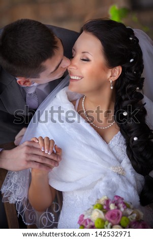 Wedding couple newlywed bride and groom in love at wedding day outdoors. Happy loving couple at bridal day embracing. newlywed with bouquet flowers. Relationship. Smiling wife and husband kiss