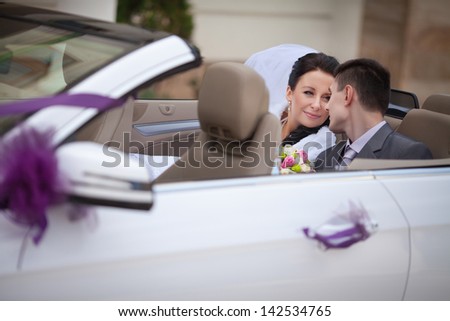 wedding couple in car bride and groom smiling in wedding car outdoors. happy loving newlywed couple embracing at bridal day. wife and husband enjoy moment of happiness. Passionate married couple