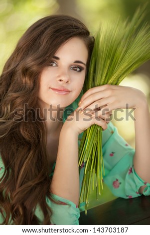 happy woman Beautiful girl smiling outdoors on green wheat field in summer nature. Pretty woman with natural makeup curly hairstyle in country village with green wheat. Attractive beauty girl in park