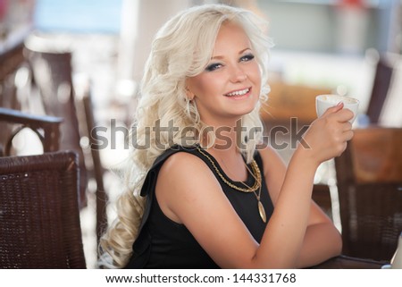 Alluring woman drinking coffee in cafe restaurant in morning sexy blonde girl with cup of latte cappuccino happy smiling. Beautiful retro woman in cafe with mug of hot chocolate. Glamour vintage woman