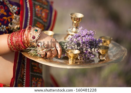 Indian girl with traditional plate of religious offerings and lavender flowers for tea ceremony. Bangles on Beautiful Jeweled Indian Dancer. Indian woman dancing in traditional dress. Indian jewelry