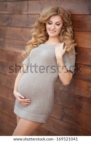 Happy pregnant woman outdoors in park. healthy pregnancy. Young pregnant girl posing in street in woolen sweater.