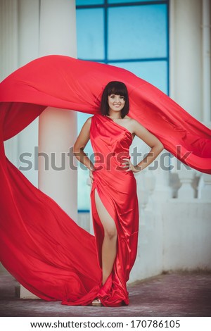 Vogue style woman in fashion red dress outdoors. Glamour beauty model in luxury red dress posing. Fashion photo of sexy woman, Vogue lady. Sensual woman in red dress. Tonned photo