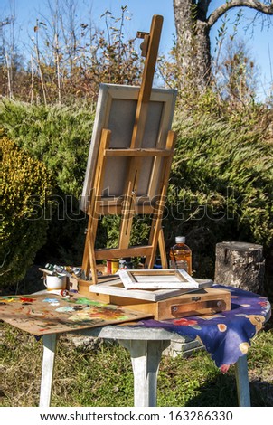 Tabletop easel for painting, palette, canvas, paint and other drawing materials artist equipment set ready for work in garden
