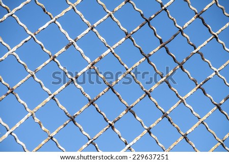 Old grunge fence net on blue sky background