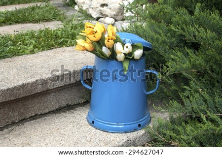 Blue retro metal enamel jug on old stone steps in back yard house garden
