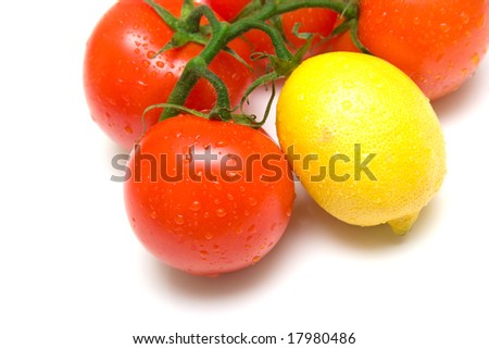 The perfect juicy tomatoes and lemon covered by drops of water, on a green branch. Isolation on white. Shallow DOF.