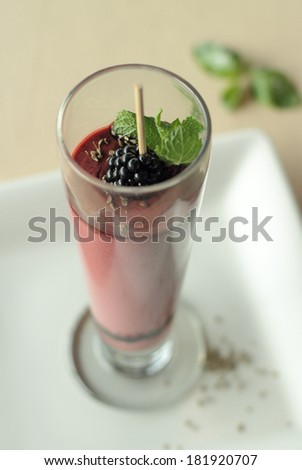 Coffee cream dessert with blackberries. Dessert of coffee cream with blackberry syrup and mint served in a tall glass and decorated with berries and anise seeds, light dessert, sweetness