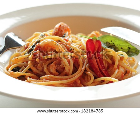 Spaghetti with crayfish. cooked dish of spaghetti with meat of crawfish and tomato sauce in white plate decorated with basil leaves and chili peppers, dish for dinner, Italian cuisine