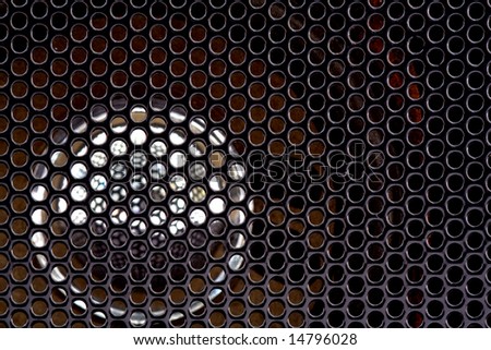This is a macro view of a automotive speaker cover with the speaker behind the metal cover.