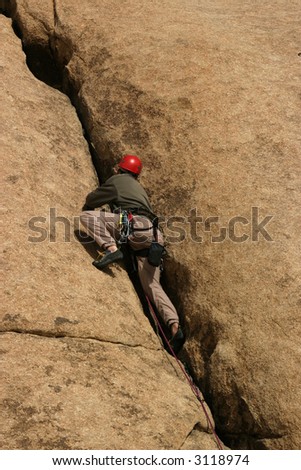 young man rock climbing with climbing gear