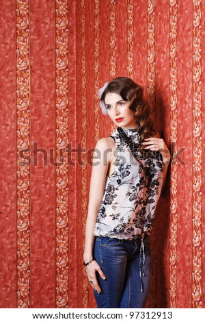 Beautiful sexy girl posing in studio leaning the wall with red wallpaper