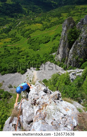Woman during rock climb high above ground