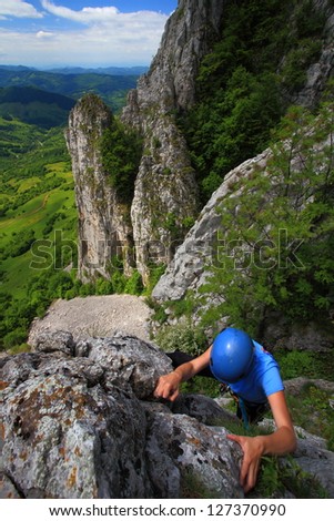 Woman climbing on the rock route during summer