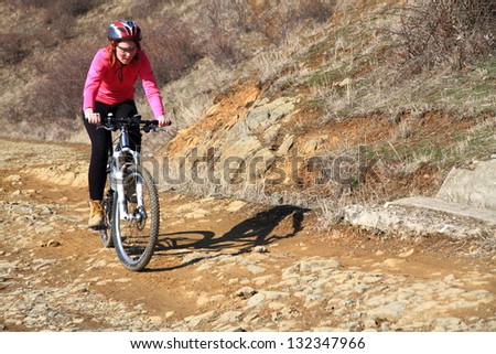 Young woman riding a mountain bike on rocky road