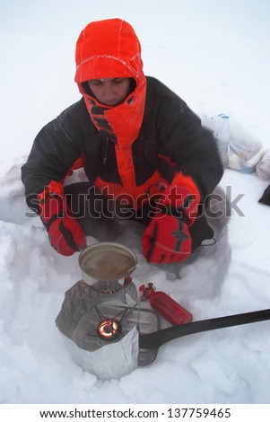 Mountaineer melting snow and cooking during winter