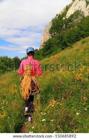 Climber woman marching to the route with the climbing gear on