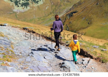 Mother and child trekking a mountain trail in fine autumn day