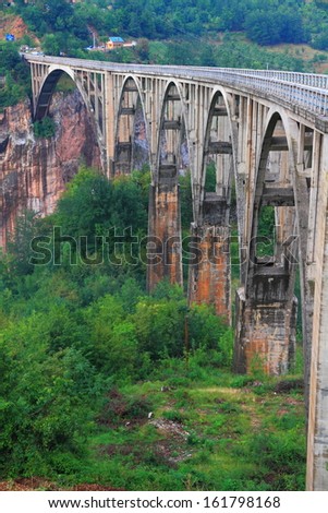 Stone bridge across deep canyon covered by vegetation