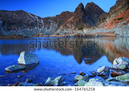 Calm mountain lake reflecting mountains before sunrise