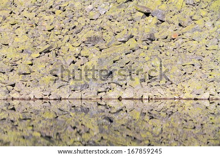 Granite rocks pattern reflected by calm lake