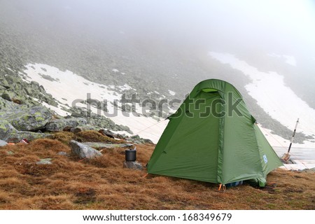 Camping site on the mountain and green tent in bad weather
