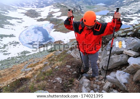 Woman ascending rough trail above frozen lake