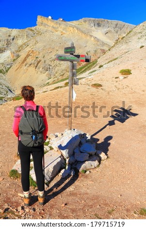 Mountain crossroads with climber searching the Lagazuoi refuge visible in the background, Dolomite Alps, Italy