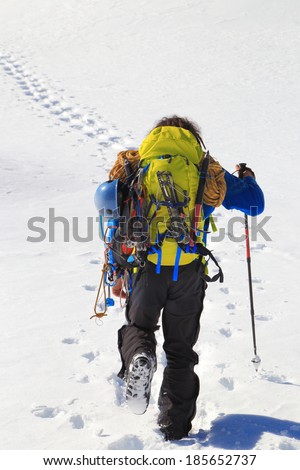 Sunny winter day with climber carrying heavy backpack on the mountain