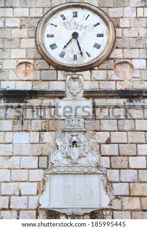 Old clock on a stone wall inside the town of Kotor