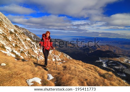 Woman carries a backpack on the side of the mountain