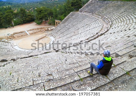 Tourist woman admires ancient Greek amphitheater, Epidaurus, Greece