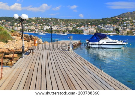 Wood deck on a pier and small boats at anchor in small harbor of Porto Rafti, Greece