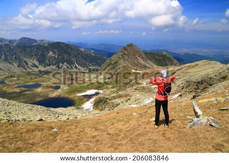 Mountain hiker standing and admiring the sunny valley in summer