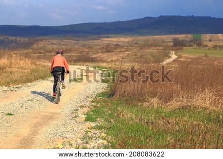 Woman descend on bike a rocky road in sunny afternoon